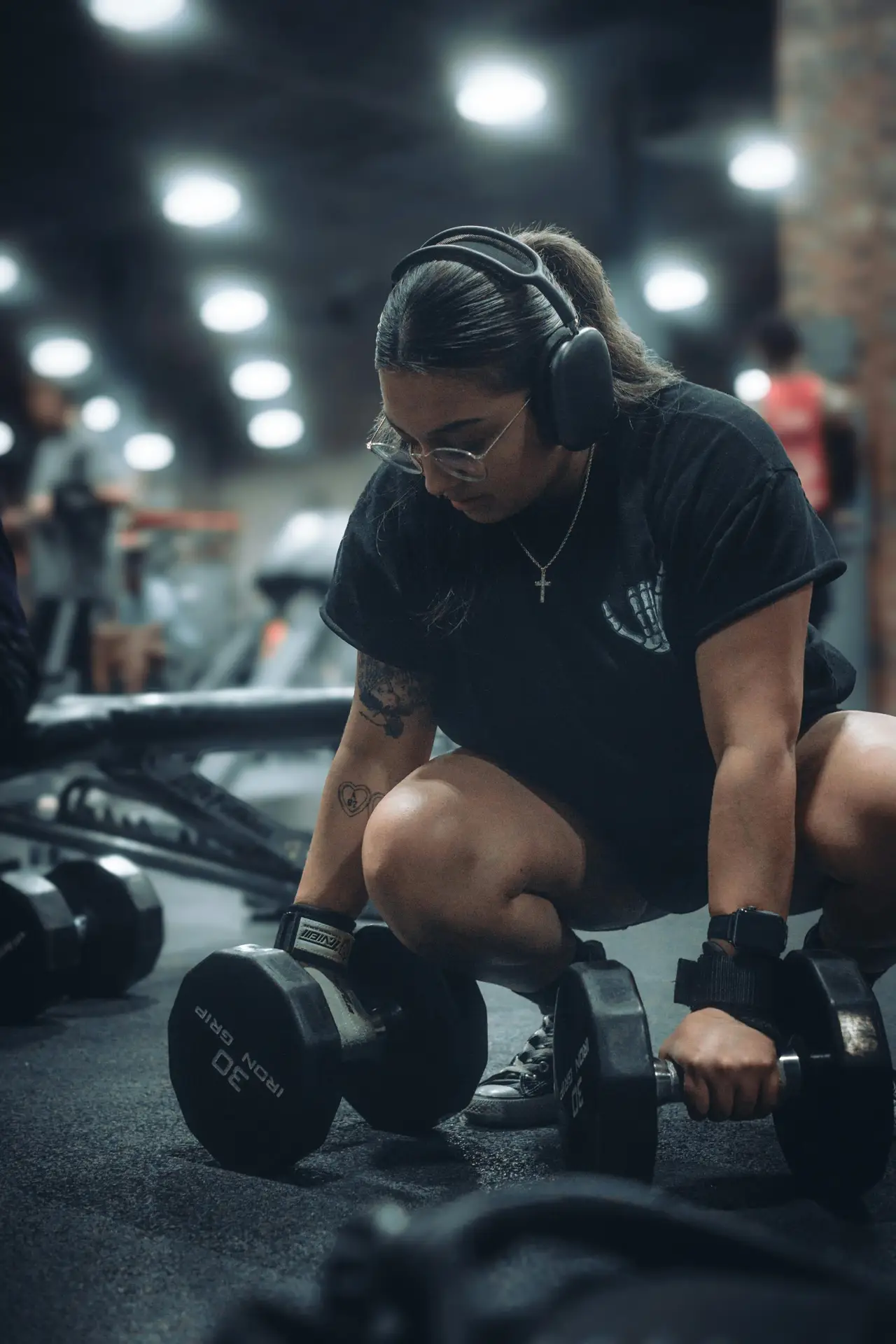 A determined woman working out with dumbbells in a gym setting, showcasing focused fitness training.